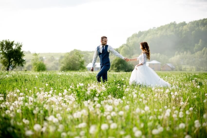 Spring wedding invitations: bride and groom walking in a meadow