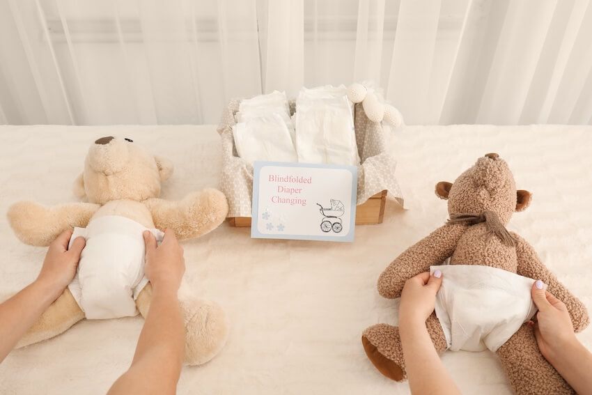 Winter wonderland baby shower: people putting diapers on two stuffed toys