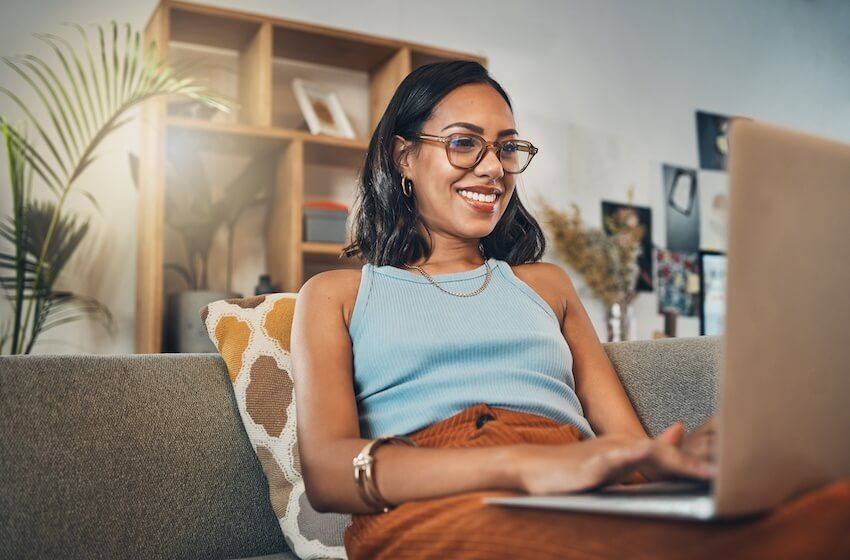 How to respond to a RSVP: woman happily using her laptop at home